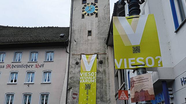 Plakate und Banner mit dem Buchstaben „V“ und den Wörtern „Vieso?“, „Veshalb?“, „Varum?“ ...