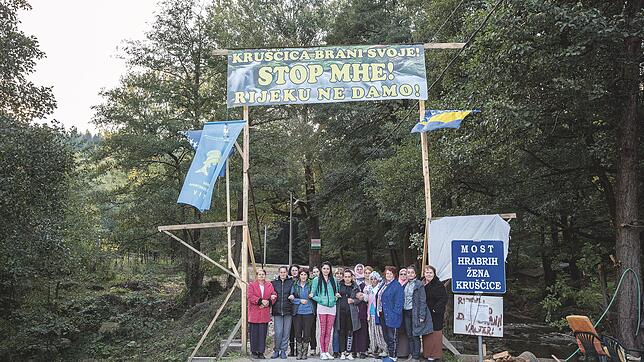 Auf dem blauen Schild rechts steht &bdquo;Brücke der mutigen Frauen von Kruscica&ldquo;, auf der Brücke selbst stehen jene Frauen, die ...