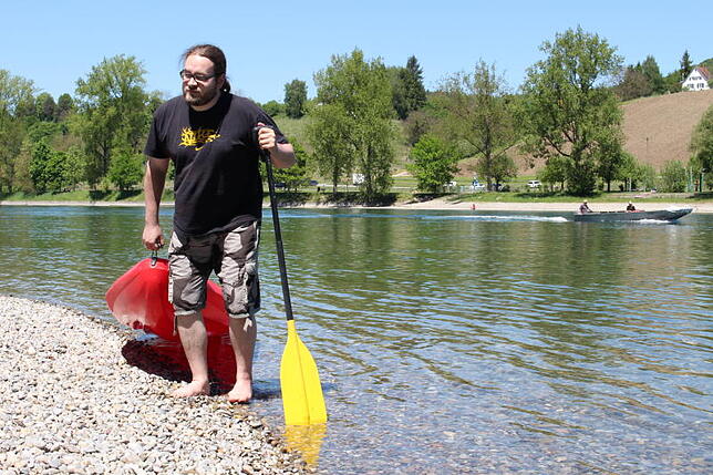 SÜDKURIER-Volontär Guy Simon zieht ein Sit-on-Top-Kanu aus dem glasklaren Rhein.