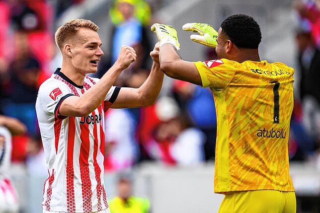 Philipp Lienhart (l, SC Freiburg) jubelt nach dem Spiel mit Torwart Noah Atubolu (SC Freiburg).
