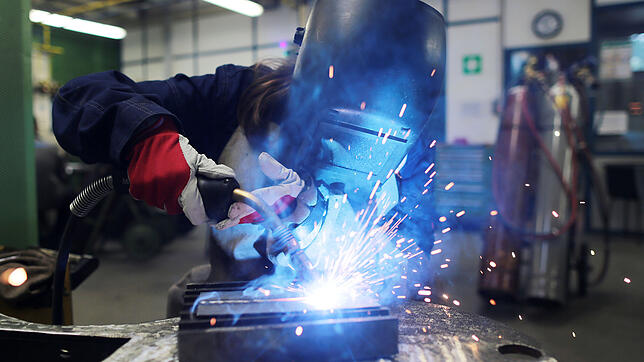 Eine Auszubildende zur Schweißerin arbeitet im Ausbildungszentrum Butzweilerhof mit einem Schweißgerät an einem Stück Metall. Allein in ...
