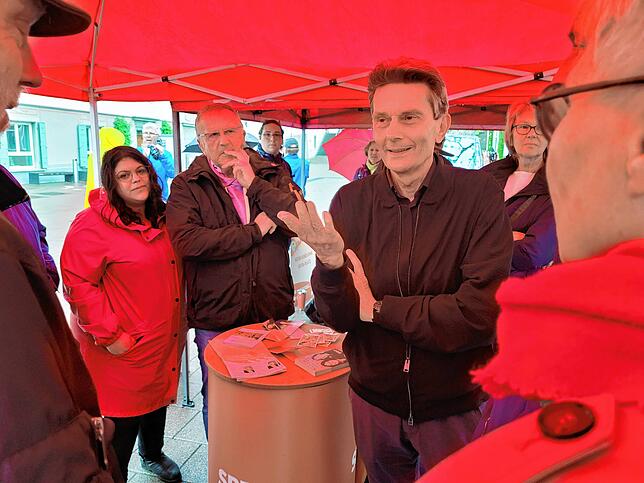 Geschützt vor dem strömenden Regen: Der SPD-Fraktionsvorsitzende Rolf Mützenich am Infostand der SPD im Gespräch mit Radolfzeller ...