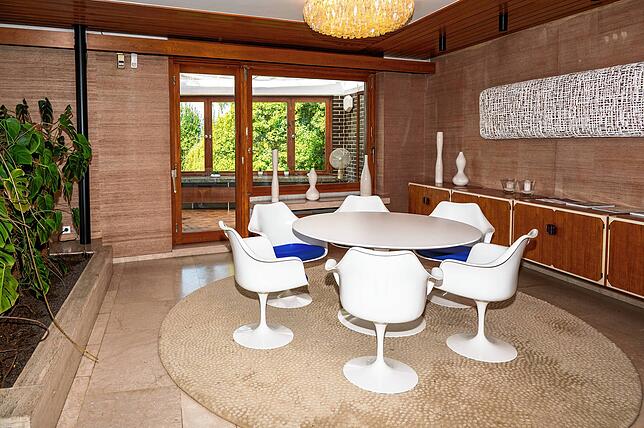 Die Zimmerpflanzen trennen das Esszimmer vom Kaminzimmer. Dahinter ist das Frühstückszimmer zu sehen.