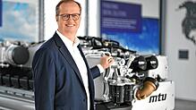 Jörg Stratmann, Vorstandsvorsitzender der Rolls-Royce Power Systems AG, steht an einem MTU-Motor der Baureihe 2000.
