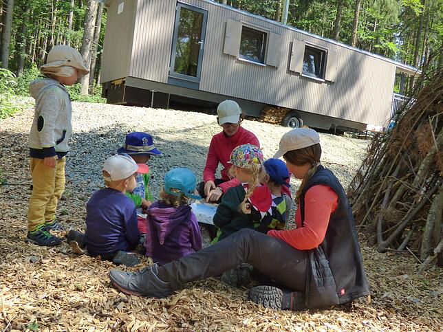 Mütze tragen ist Pflicht im Waldkindergarten &ndash; hier schauen sich die Kinder gemeinsam mit den Erzieherinnen Franziska Nusser und ...