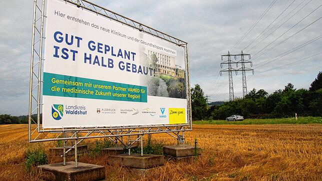 Ein Plakat weist auf den hier geplanten Gesundheitspark und das zukünftige Zentralkrankenhaus hin. Im Hintergrund ist die B 34 zu sehen.