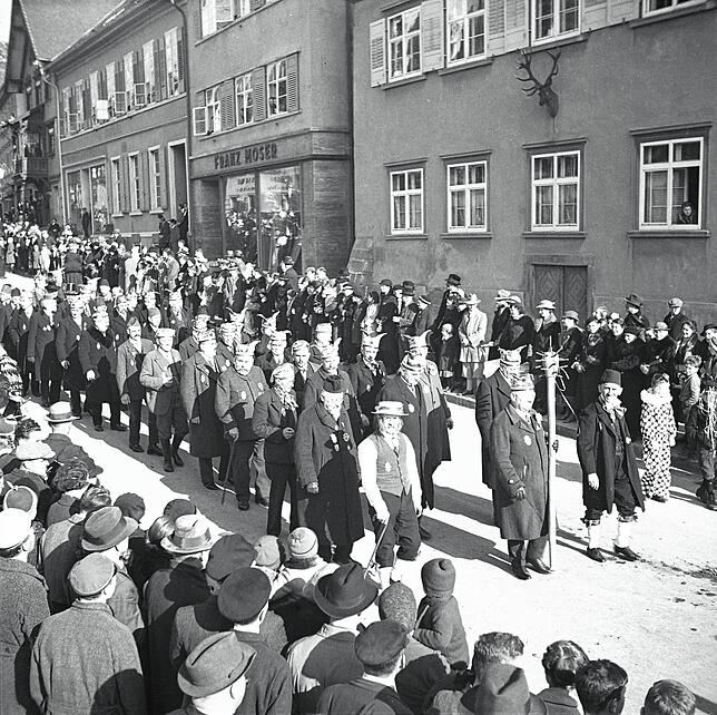 Umzug durch die Hauptstraße. Das Gebäude im Hintergrund sieht heute etwas anders aus. Heute ist es das Alte Forstamt.