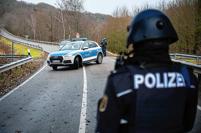 Polizeibeamte stehen an einer Absperrung an der Kreisstraße 22 rund einen Kilometer von dem Tatort, an dem zwei Polizeibeamte durch ...