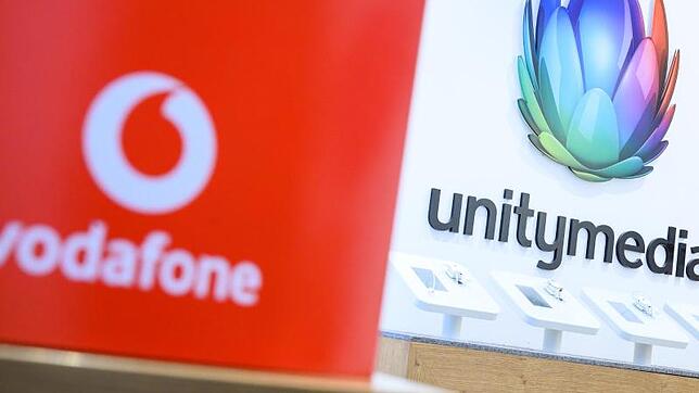 Eine Box mit dem Logo von Vodafone steht in einem Shop des Unternehmens vor einem Logo von Unitymedia.