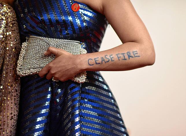 Shruti Ganguly trägt einen roten Button und am Arm den Schriftzug &bdquo;Cease Fire&ldquo; (&ldquo;Feuer einstellen&ldquo;) als ...