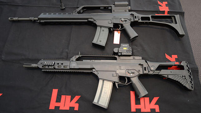 Zwei Sturmgewehre G36 von Heckler und Koch liegen in Oberndorf (Baden-Württemberg) in der Firmenzentrale auf einem Tisch vor einem Logo ...