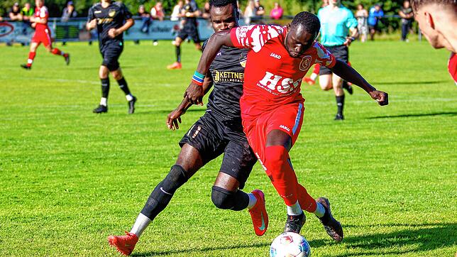 Alieu Sarr (rotes Trikot) im Zweikampf mit dem Stürmer vom FC Pfaffenweiler, Jallow Saja (schwarzes Trikot). Der FC Königsfeld ist ...