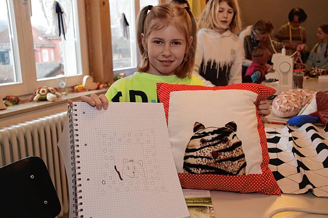 Stolz präsentiert Caroline (9) ihre Skizze und das fertige Kisseen, das sie selbst geschaffen hat.