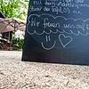 Eine Tafel mit den Worten &bdquo;Wir freuen uns auf Euch&ldquo; steht auf einer Tafel am Eingang einer Gartenterrasse. Ab 30. Mai dürfen ...