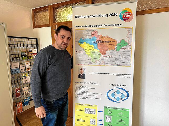 Tobias Hofmann an einer Karte, die die neuen Großpfarreien zeigt.