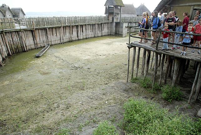 Eine Besuchergruppe bestaunt in Unteruhldingen am Bodensee die Pfahlbauten, die teilweise auf dem Trockenen stehen.
