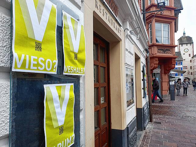 Plakate mit dem Buchstaben V hängen in der Waldshuter Altstadt.