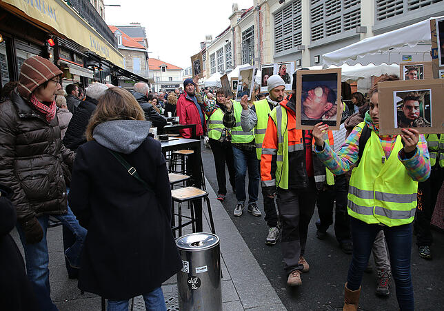 Demonstranten in gelben Westen halten Fotos von Menschen, die in den letzten Wochen angeblich Opfer von Polizeigewalt geworden sind.