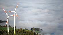 08.10.2018, Baden-Württemberg, Horben: Zwei Windräder stehen am Fuße des Berges Schauinsland im Schwarzwald über dem Nebelmeer im Tal. ...