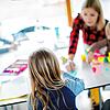 Eine Mutter, selbst von Beruf Lehrerin, sitzt mit ihren drei Kindern im Wohnzimmer und hilft ihnen bei ihren Aufgaben für die Schule. ...