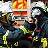 (Symbolbild) Zwei Feuerwehrmänner schließen sich während einer Übung vor einem Löschfahrzeug die Atemschutzgeräte an.