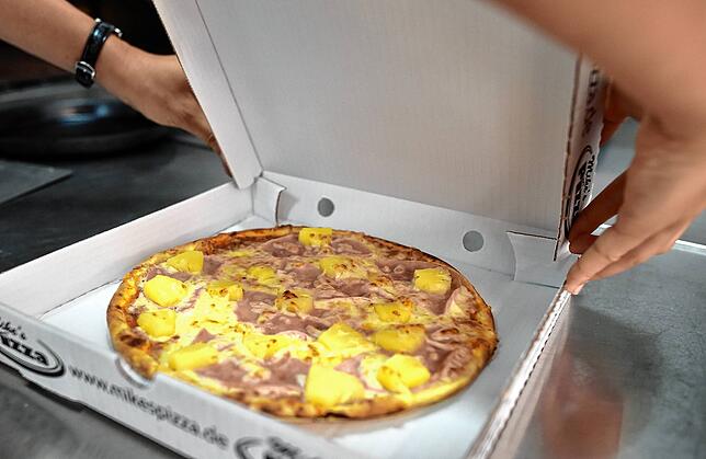 Eine Pizza Hawaii wird bei einem Pizza-Lieferservice verpackt.