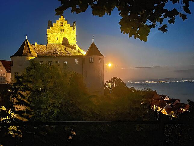 Der Vollmond über und neben der Mittelalterburg Meersburg, aufgenommen vom Dr.-Moll-Platz aus am Abend des 11. Augusts 2022.