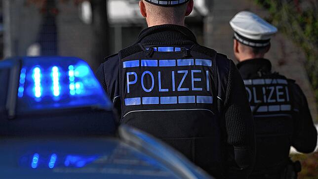 Polizisten stehen bei ihrem Einsatzwagen (Symbolbild). Nach einer Großfahdnung am Hochrhein wird in Waldshut ein 23-Jähriger festgenommen.