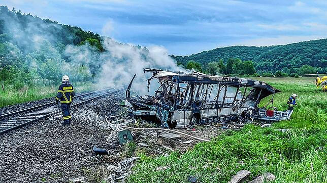 Die Feuerwehr löscht den Brand in dem Bus, der in der Nähe von Ulm mit einem Zug kollidierte.
