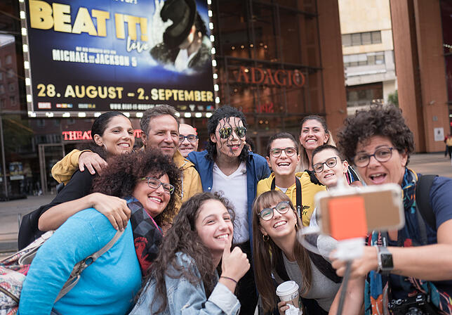 Touristen machen mit dem Musical-Darsteller Dantanio Goodman vor dem Theater am Potsdamer Platz in Berlin ein Selfie.