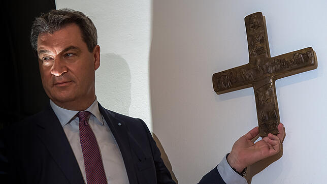 Markus Söder, Bayerischer Ministerpräsident (CSU), hängt ein Kreuz im Eingangsbereich der bayerischen Staatskanzlei auf.