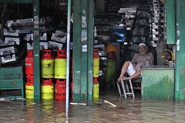 Ein sitzt in Dhaka (Bangladesch) in seinem Laden, der durch heftige Regenfälle überschwemmt worden ist. Der Klimawandel verstärkt die ...