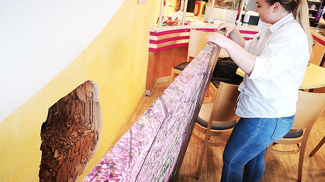 Bäckereiangestellte Susanna Wagner zeigt das Loch, das die Täter in die Wand gebohrt haben. Bis der Schaden repariert ist, verdeckt ein ...