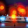 Ein Feuerwehrauto mit Blaulicht vor rot reflektierenden Lichtern.