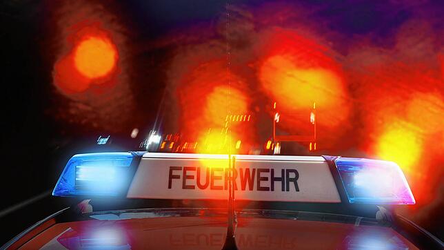 Ein Feuerwehrauto mit Blaulicht vor rot reflektierenden Lichtern.