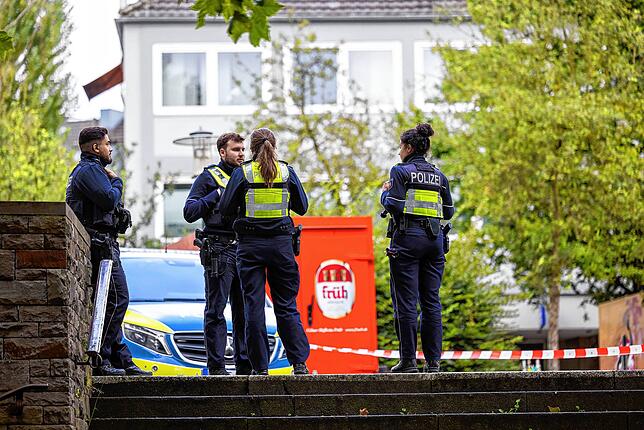 Einsatzfahrzeuge und Beamte der Polizei stehen am frühen Morgen an einer Absperrung in der Innenstadt.