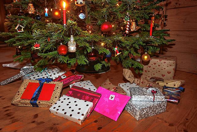 Verpackte Weihnachtsgeschenke unterm geschmückten Weihnachtsbaum &ndash; darin steckt nicht immer etwas Gutes.