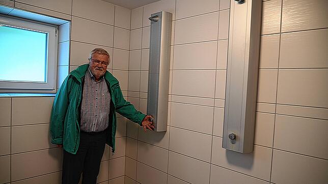 Gerhard Mengesdorf, TV-Vorsitzender, steht neben der Duschsäule in der vereinseigenen Turnhalle mit der Hand am Einstellthermostat.