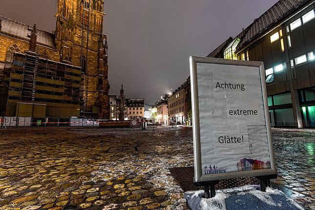 Ein Schild mit der Aufschrift &bdquo;Achtung extreme Glätte!&ldquo; steht auf dem Münsterplatz in Freiburg. Schneefälle und gefährliches ...