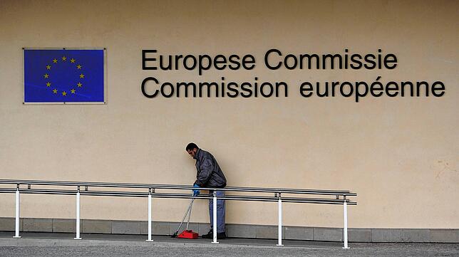 Ein Mann kehrt vor der EU-Kommission Müll auf. Er zählt sicher nicht zu den gut  bezahlten Beamten.